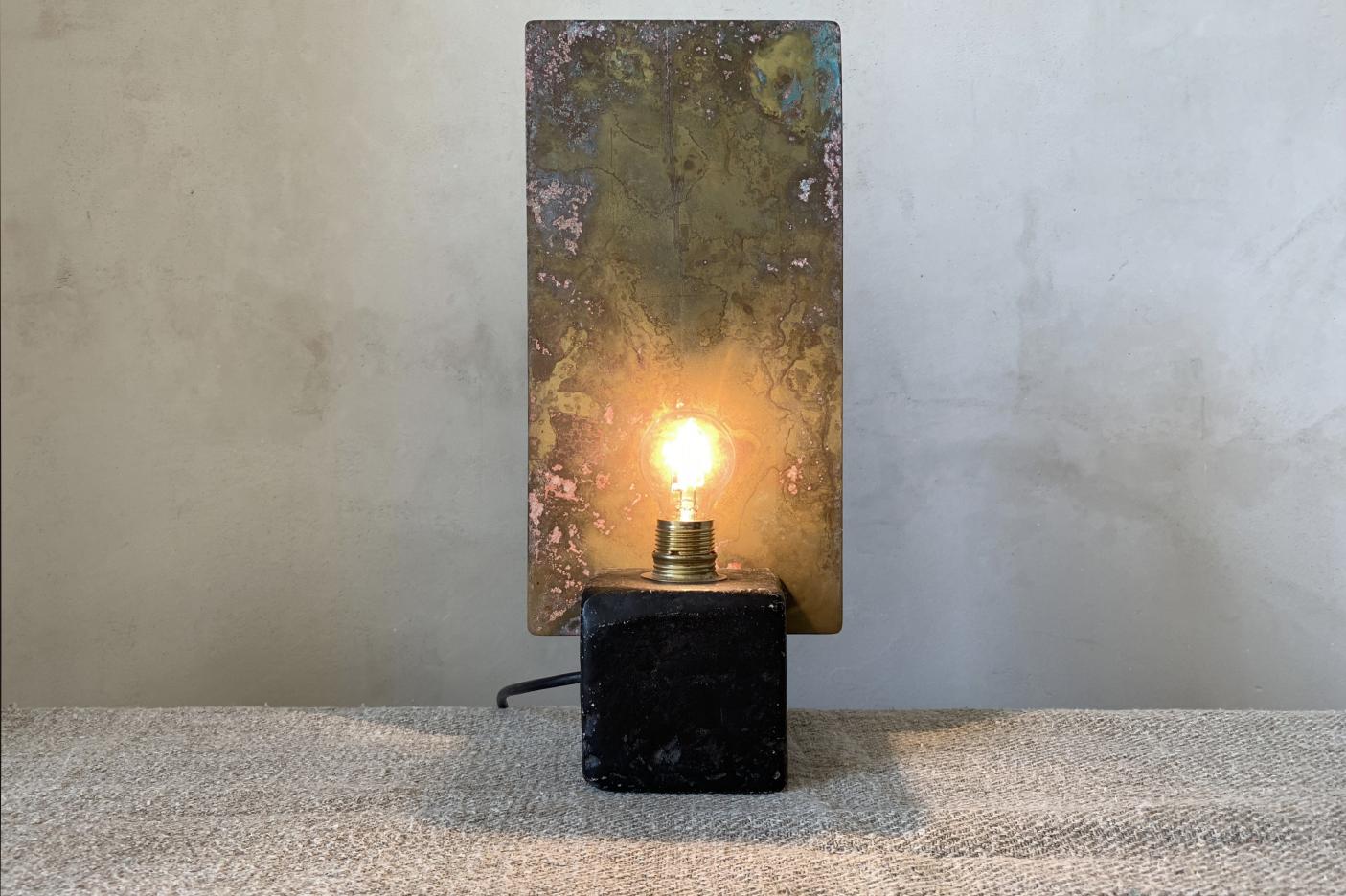 SCULPTURAL LIGHTING. TABLE LAMP IN BRASS AND CONCRETEconcrete base: carbon black / brass light reflector: antique gold, oxidized brass